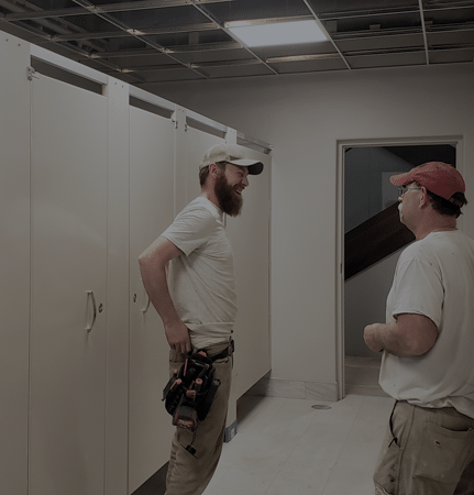 Installers reviewing a restroom partition installation